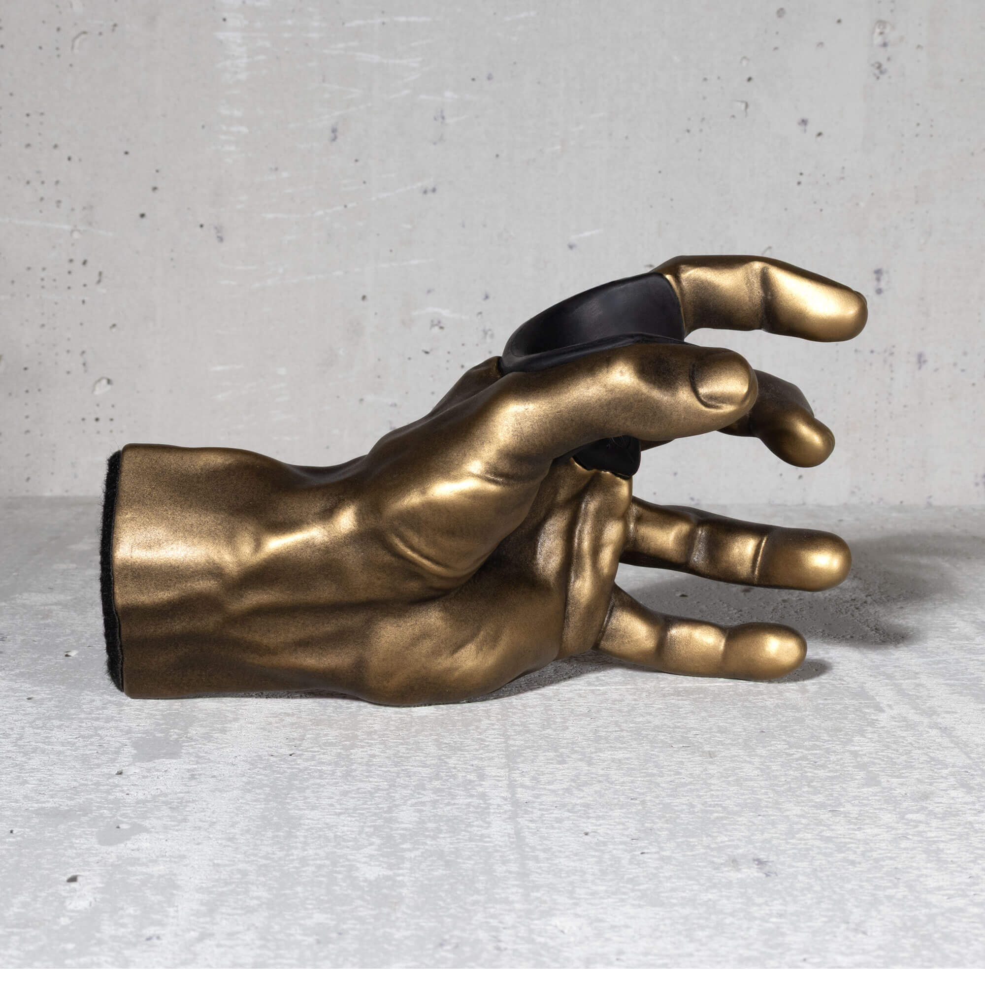Gold hand sculpture guitar hanger on a gray surface.