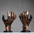 Pair of copper hand guitar hangers on grey wall.