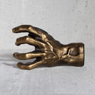 Gold hand sculpture wall hanger for guitars on a gray background.