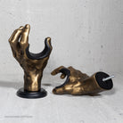 Gold hand-shaped guitar hangers on a gray surface.

