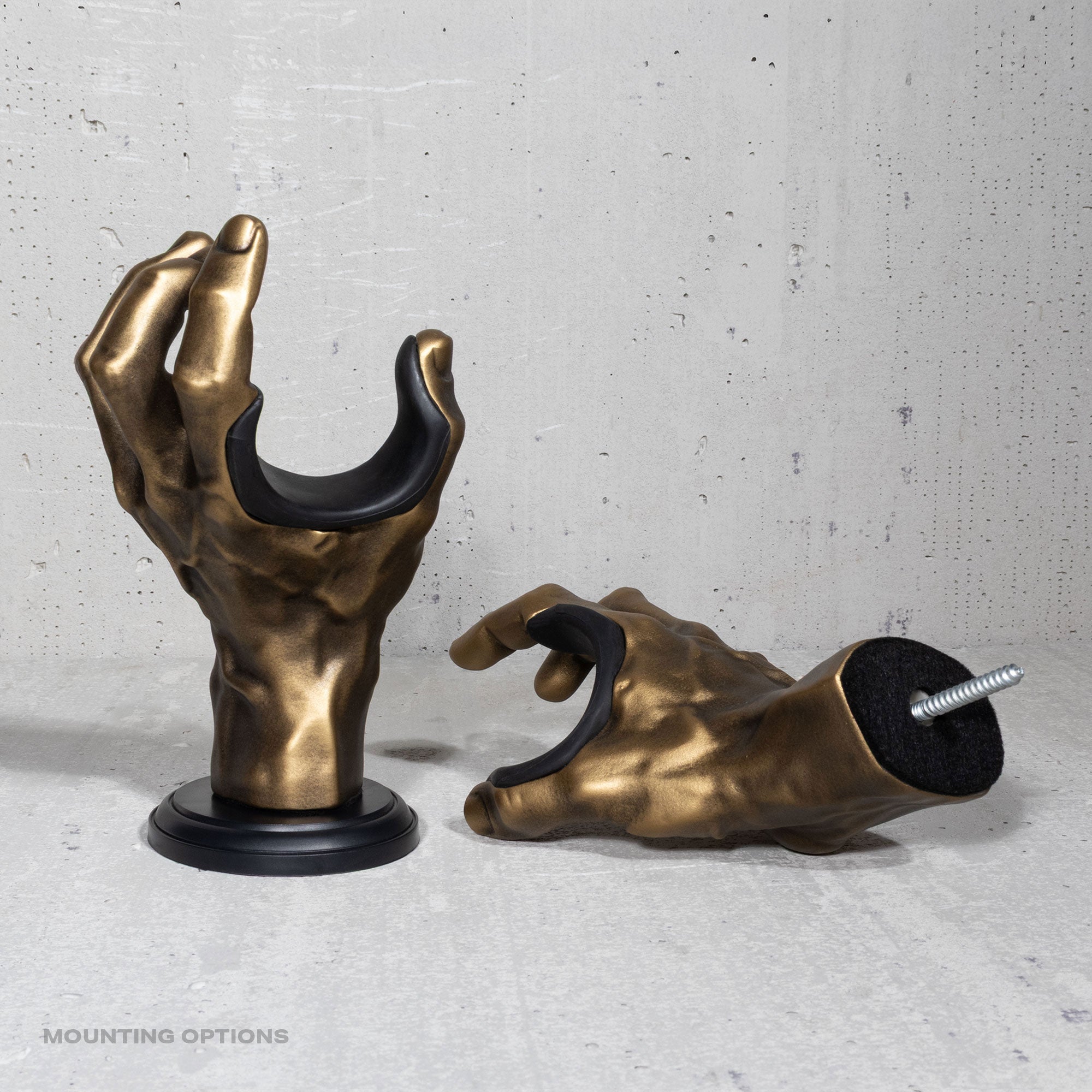 Gold hand-shaped guitar hangers on a gray surface.

