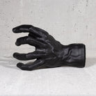Black hand guitar hook wall mount on grey background.