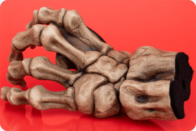 Skeleton hand guitar hanger on a red background used for hanging guitars on the wall. 
