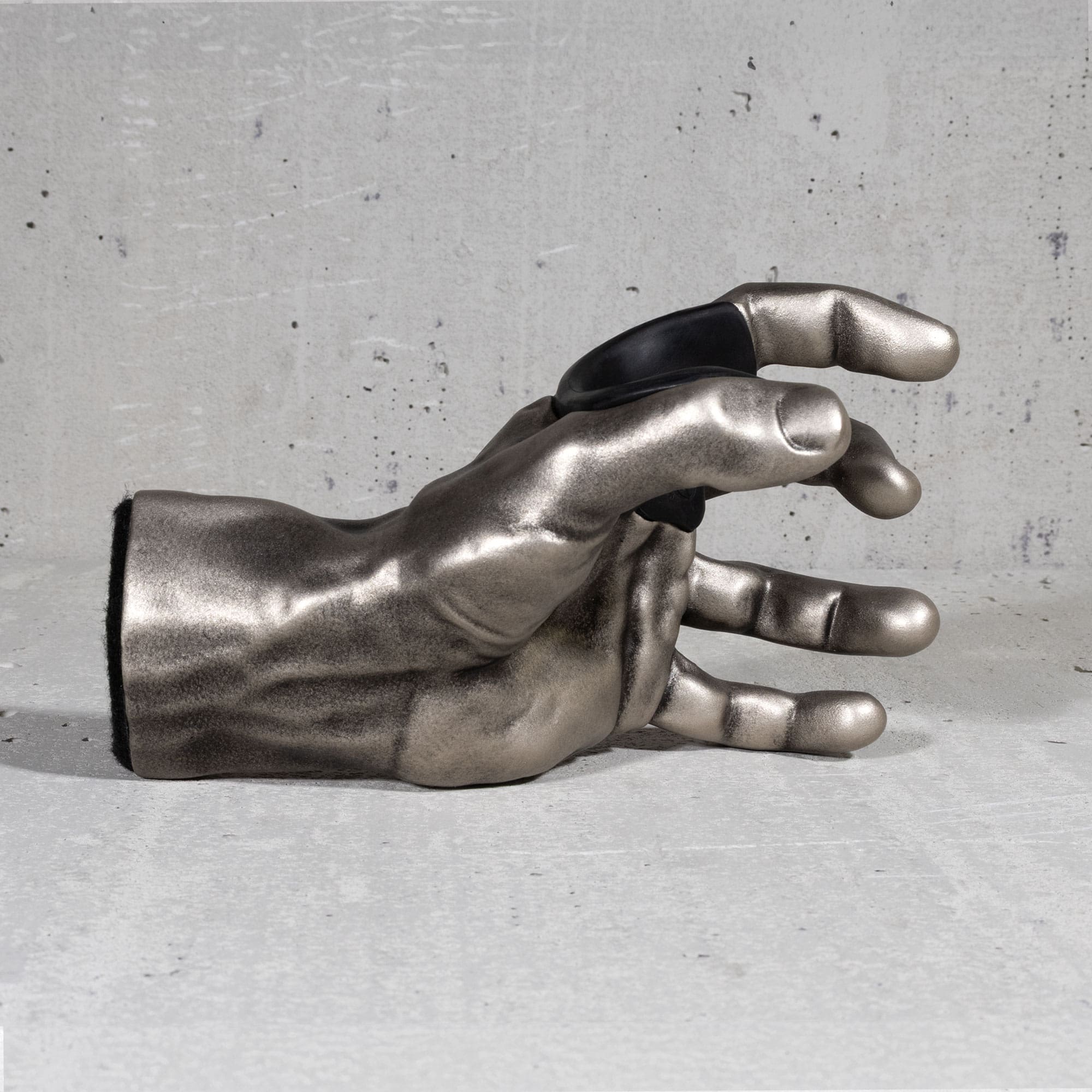 Metallic hand sculpture  guitar hanger on a gray concrete surface

