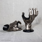 GuitarGrip metallic hand-shaped guitar wall mounts on a concrete surface.

