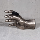 Inside view of antiqued silver hand used to mount instruments, specifically guitars, to the wall. 