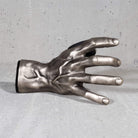 Metallic hand sculpture guitar hanger wall mount. on a gray surface

