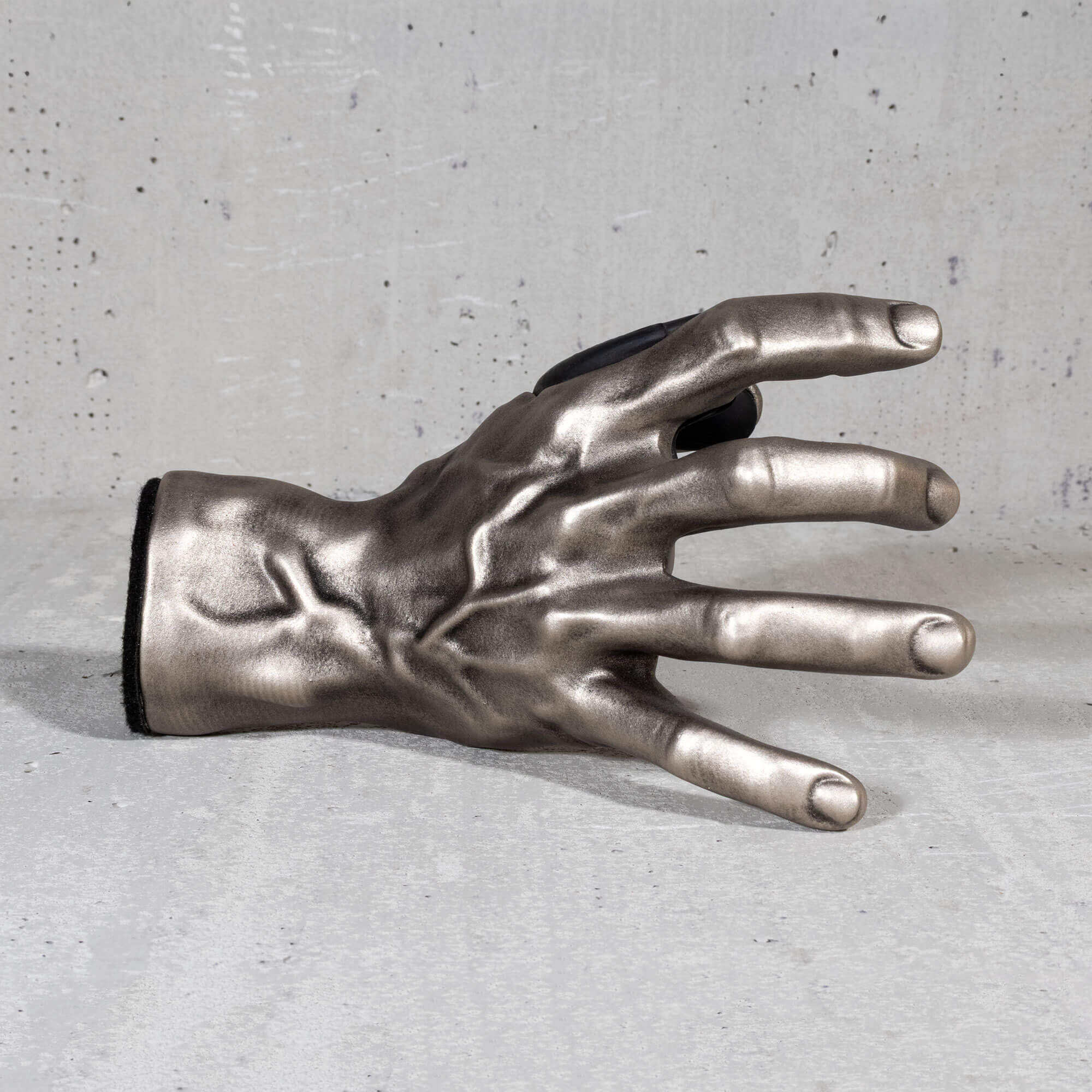 Metallic hand sculpture guitar hanger wall mount. on a gray surface

